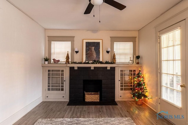 living room featuring hardwood / wood-style flooring, ceiling fan, and a tiled fireplace