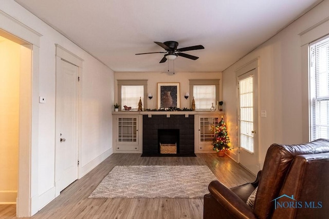 living room featuring hardwood / wood-style floors, ceiling fan, and a fireplace