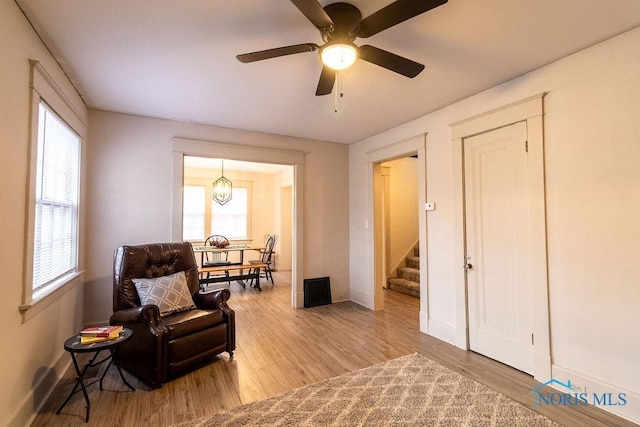 sitting room with ceiling fan with notable chandelier, light wood-type flooring, and a wealth of natural light