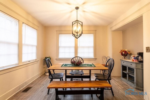 dining space with hardwood / wood-style floors and a notable chandelier