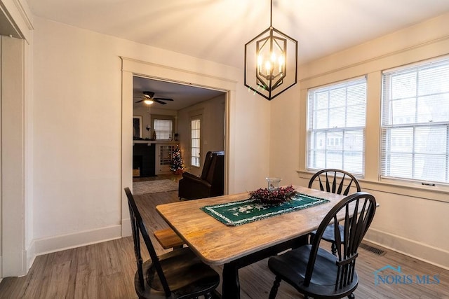 dining space featuring ceiling fan with notable chandelier and dark wood-type flooring