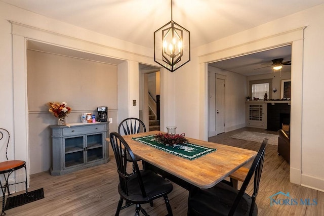 dining room featuring ceiling fan with notable chandelier and wood-type flooring