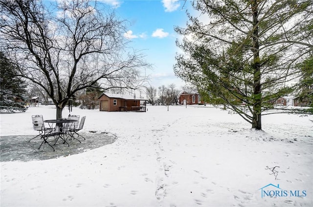 yard layered in snow featuring an outbuilding