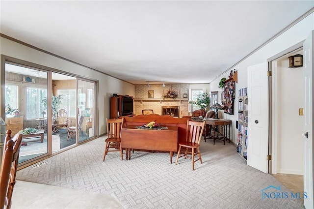 carpeted dining area featuring a fireplace, a wealth of natural light, and crown molding