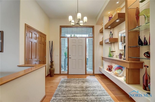 foyer entrance with light hardwood / wood-style floors and an inviting chandelier