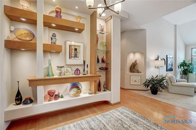 interior space with hardwood / wood-style floors, vaulted ceiling, and a notable chandelier