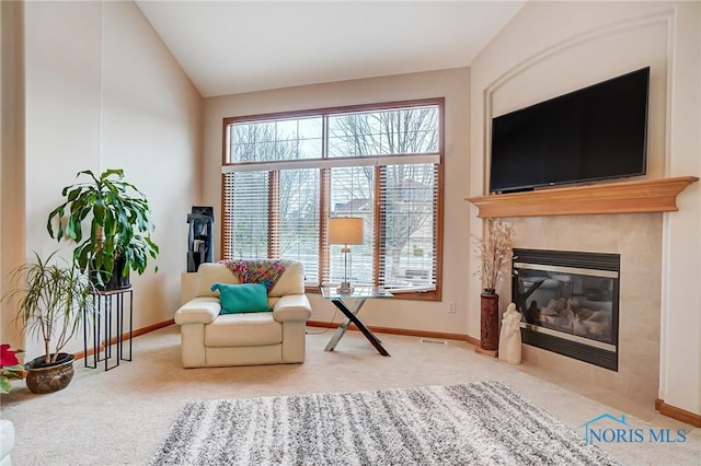 sitting room with carpet, a healthy amount of sunlight, vaulted ceiling, and a tiled fireplace