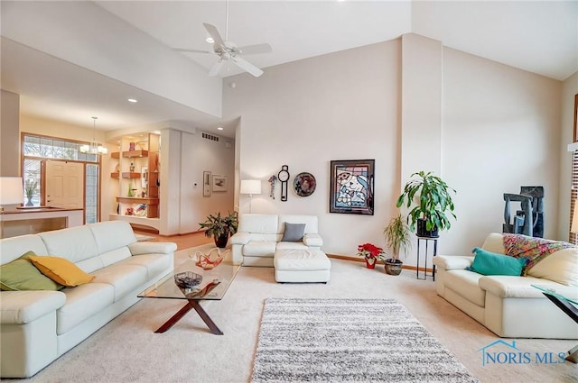 carpeted living room with ceiling fan with notable chandelier and high vaulted ceiling