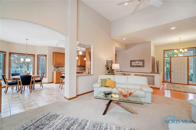 carpeted living room featuring plenty of natural light and ceiling fan with notable chandelier