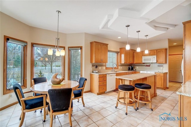 kitchen with a center island, sink, hanging light fixtures, white appliances, and light tile patterned flooring