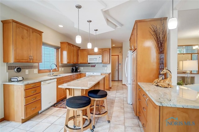 kitchen featuring white appliances, a kitchen breakfast bar, sink, decorative light fixtures, and kitchen peninsula