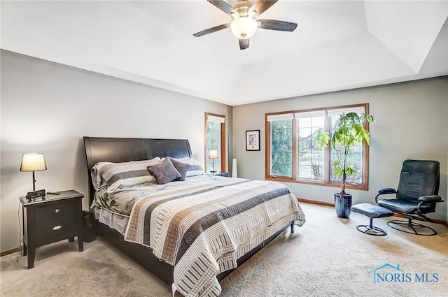 carpeted bedroom featuring ceiling fan and a tray ceiling