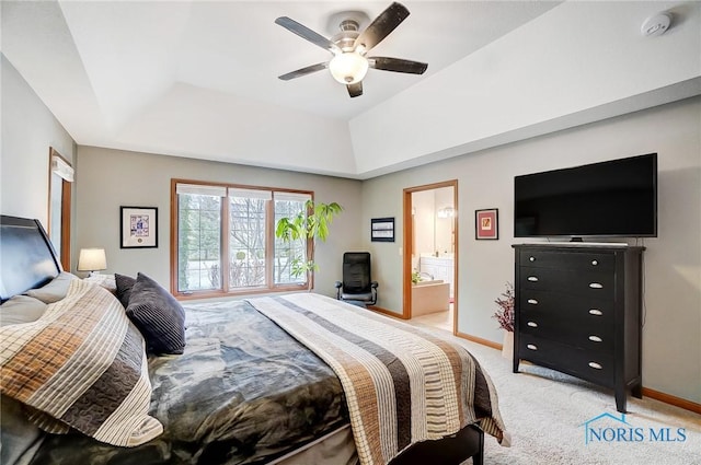 bedroom with ensuite bathroom, ceiling fan, a raised ceiling, and light carpet