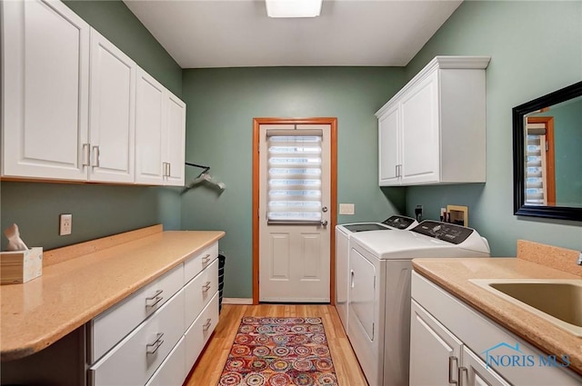 laundry room with cabinets, light hardwood / wood-style floors, washing machine and dryer, and sink