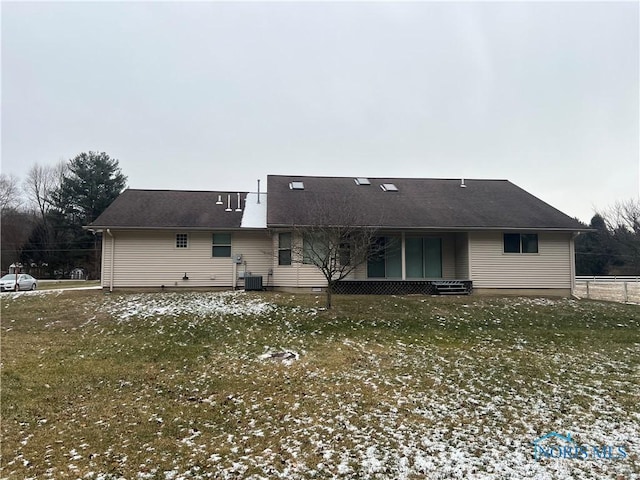 back of property with central air condition unit and a lawn