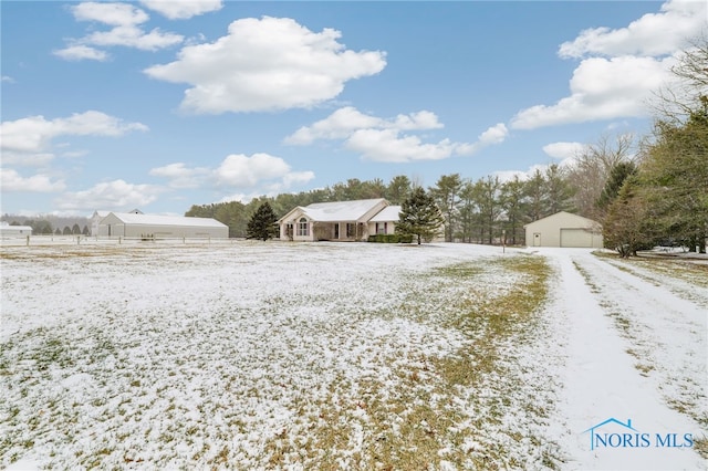 yard covered in snow featuring a garage and an outbuilding