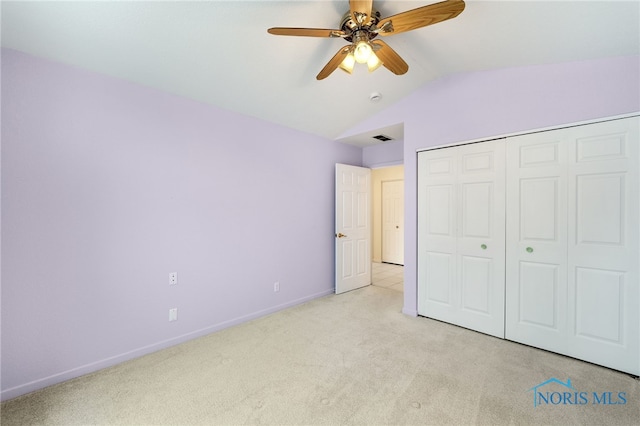 unfurnished bedroom with vaulted ceiling, ceiling fan, a closet, and light carpet