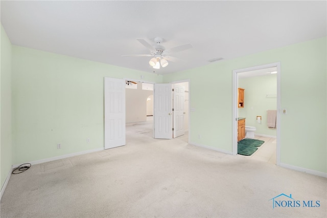 unfurnished bedroom with light colored carpet, ceiling fan, and connected bathroom