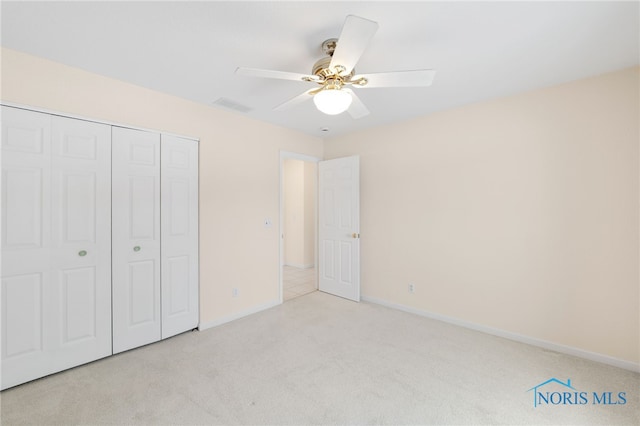 unfurnished bedroom with light carpet, a closet, and ceiling fan