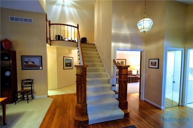 stairs with wood-type flooring and a towering ceiling