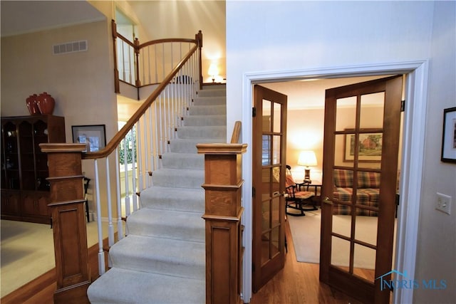 staircase featuring wood-type flooring and french doors