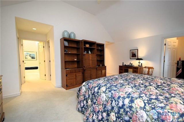 bedroom with ensuite bathroom, lofted ceiling, and light carpet