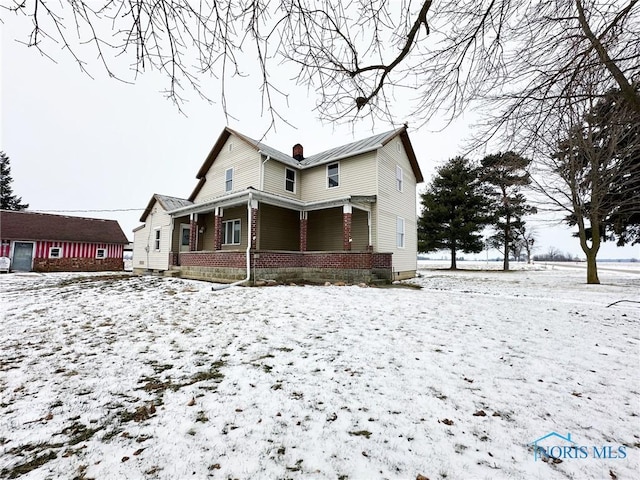 snow covered back of property with a porch