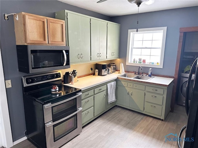 kitchen with sink, ceiling fan, light wood-type flooring, stainless steel appliances, and washer / clothes dryer