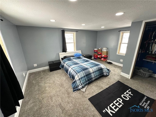 carpeted bedroom featuring a walk in closet, a textured ceiling, and a closet