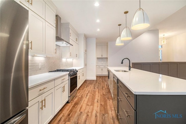 kitchen featuring white cabinetry, appliances with stainless steel finishes, a kitchen island with sink, wall chimney range hood, and pendant lighting