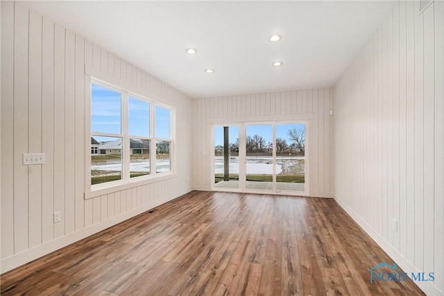 empty room with a water view, wood-type flooring, and wooden walls