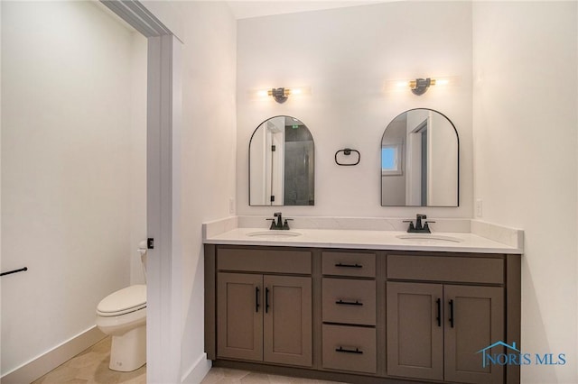 bathroom with toilet, vanity, and tile patterned flooring