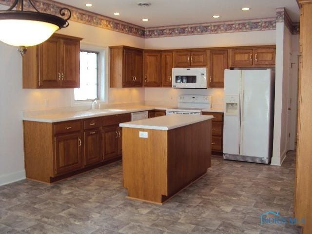 kitchen featuring sink, a kitchen island, decorative light fixtures, and white appliances