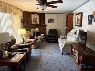 carpeted living room featuring ceiling fan and a fireplace