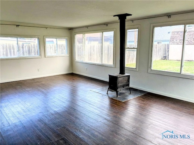 unfurnished sunroom featuring a wood stove and plenty of natural light