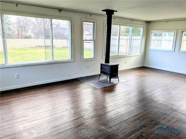 unfurnished living room with a wood stove and dark hardwood / wood-style flooring