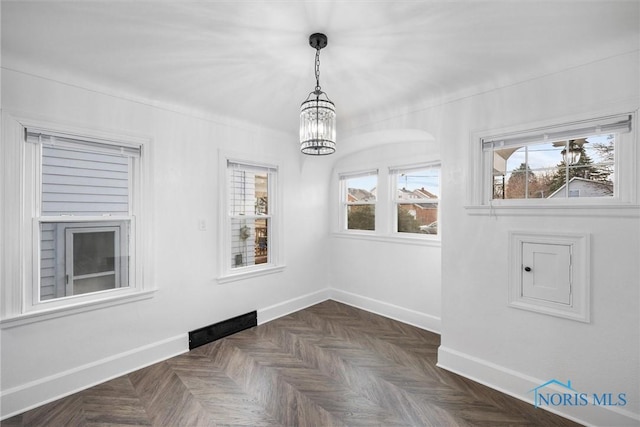 spare room with dark parquet floors and a chandelier