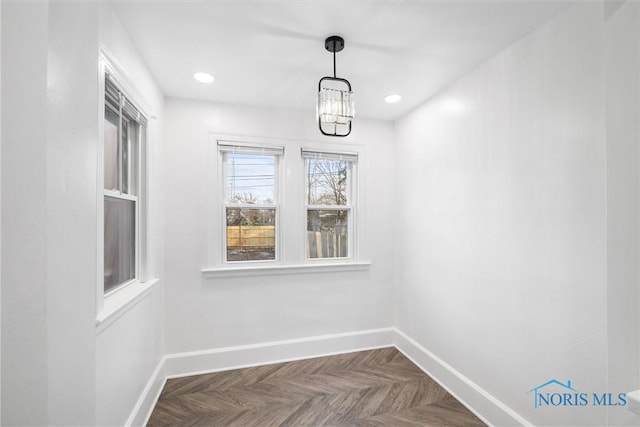 unfurnished dining area featuring a chandelier and dark parquet floors