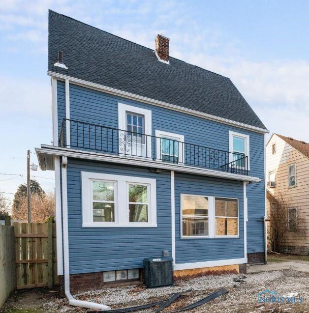 rear view of house with central AC unit and a balcony