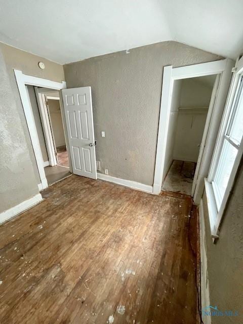 unfurnished bedroom with hardwood / wood-style flooring, a closet, and lofted ceiling