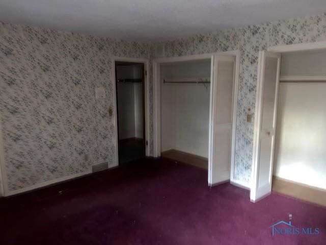 unfurnished bedroom featuring multiple closets