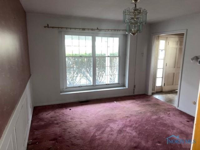 unfurnished room featuring carpet and a notable chandelier