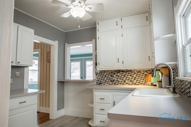 kitchen featuring sink, ceiling fan, backsplash, and white cabinetry