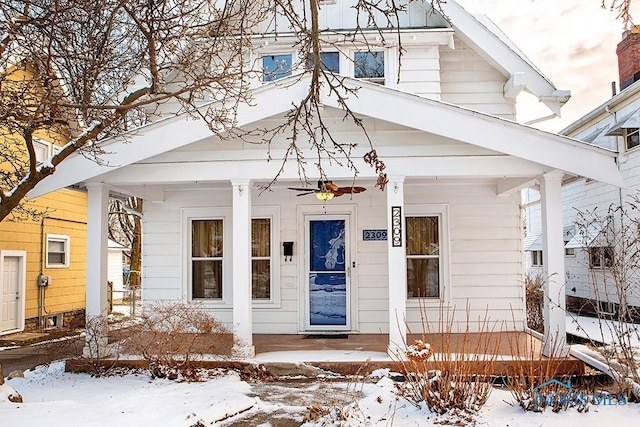 snow covered property entrance featuring covered porch