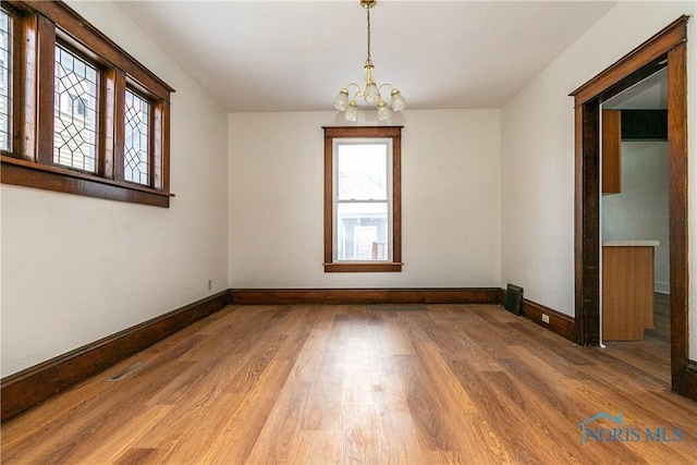 empty room featuring a chandelier and hardwood / wood-style flooring