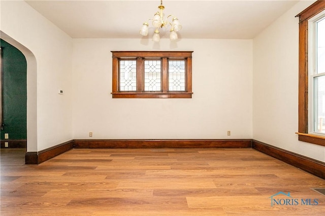 empty room featuring a notable chandelier and wood-type flooring