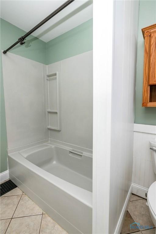 bathroom featuring tile patterned flooring, shower / bathtub combination, and toilet