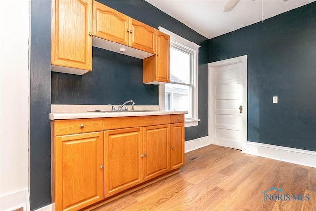 kitchen featuring ceiling fan, sink, and light hardwood / wood-style flooring