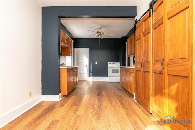 kitchen featuring a barn door, light hardwood / wood-style flooring, white electric stove, and ceiling fan