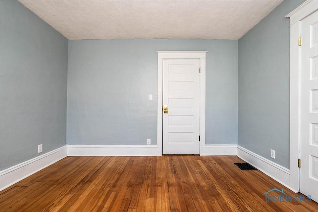 unfurnished room featuring dark wood-type flooring and a textured ceiling